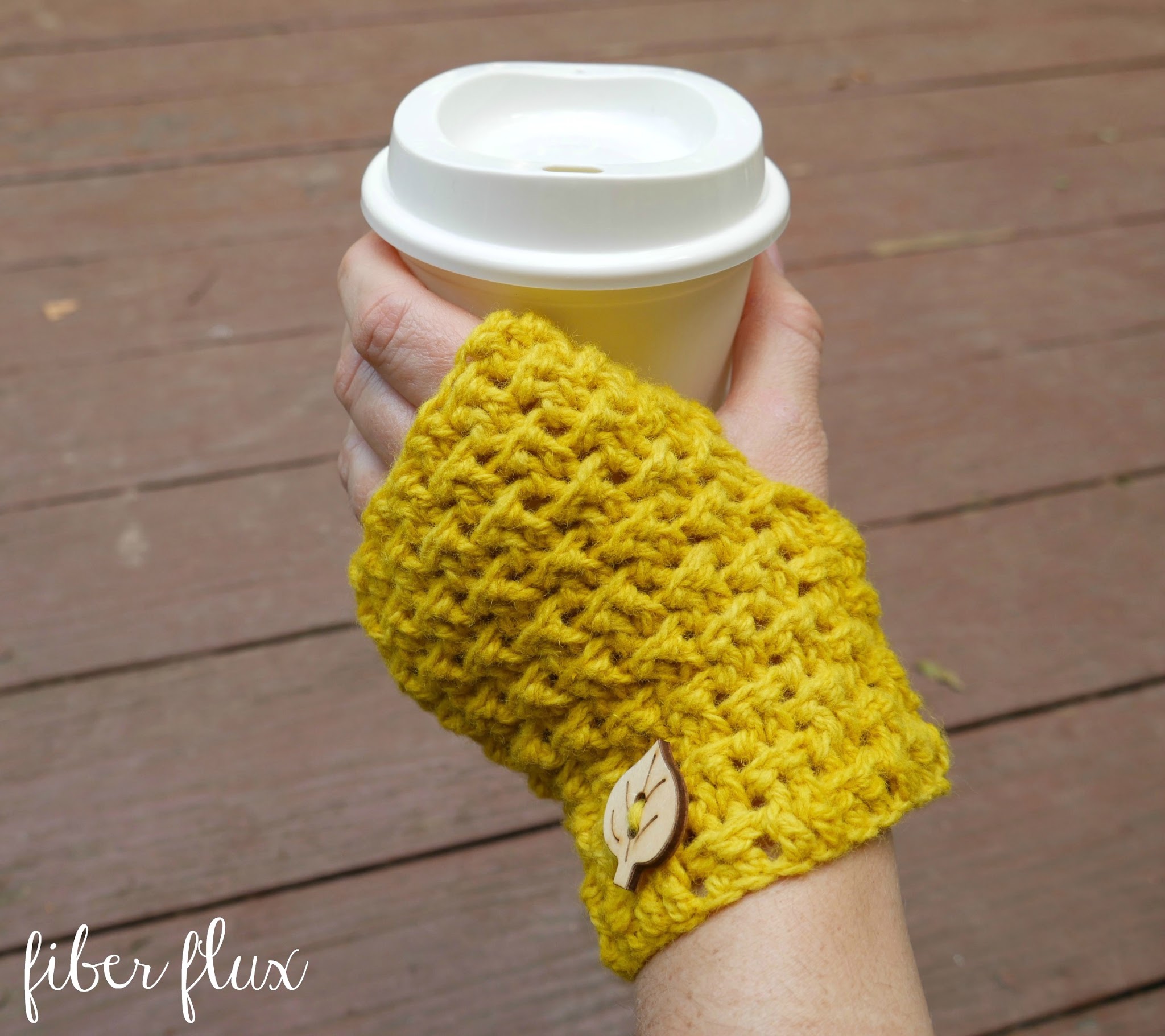 Autumn Glow crochet fingerless mitts shown holding a cup